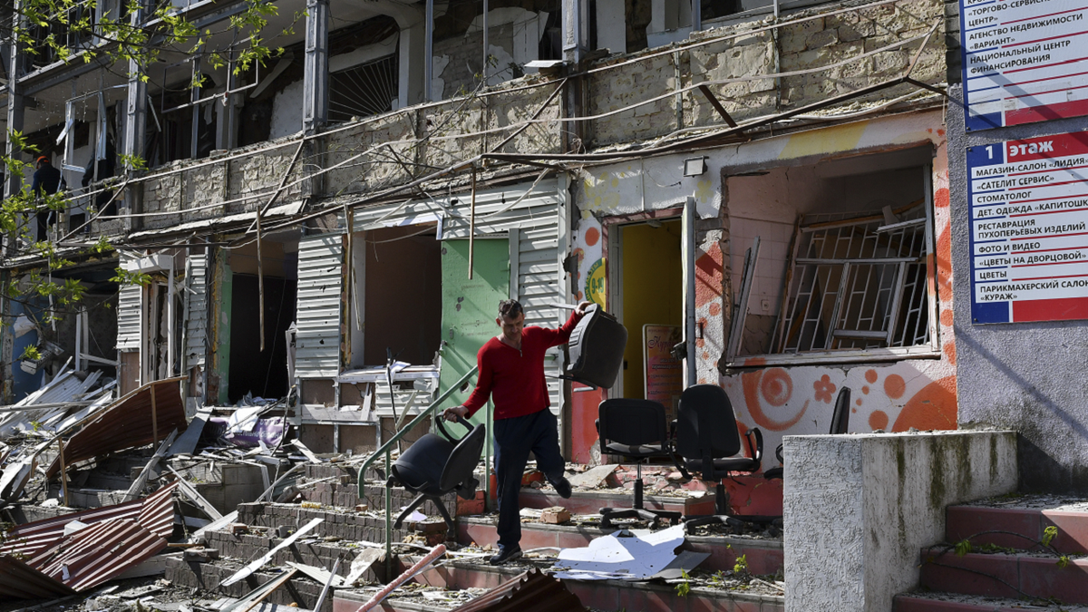 A man carries chairs out of an office on a ground floor of an apartment building destroyed by night shelling in Kramatorsk, Ukraine, on Thursday, May 5.