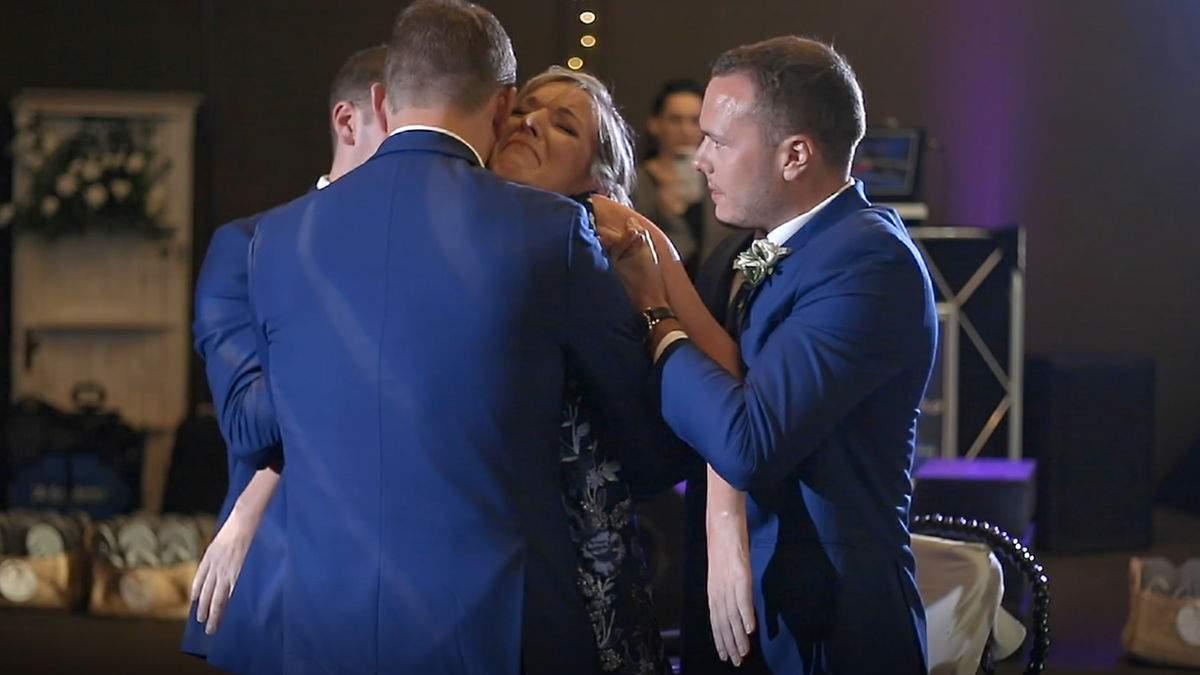 Zak and Kathy Poirer dance at his wedding while brother Nick and Jake offer standing support for Kathy