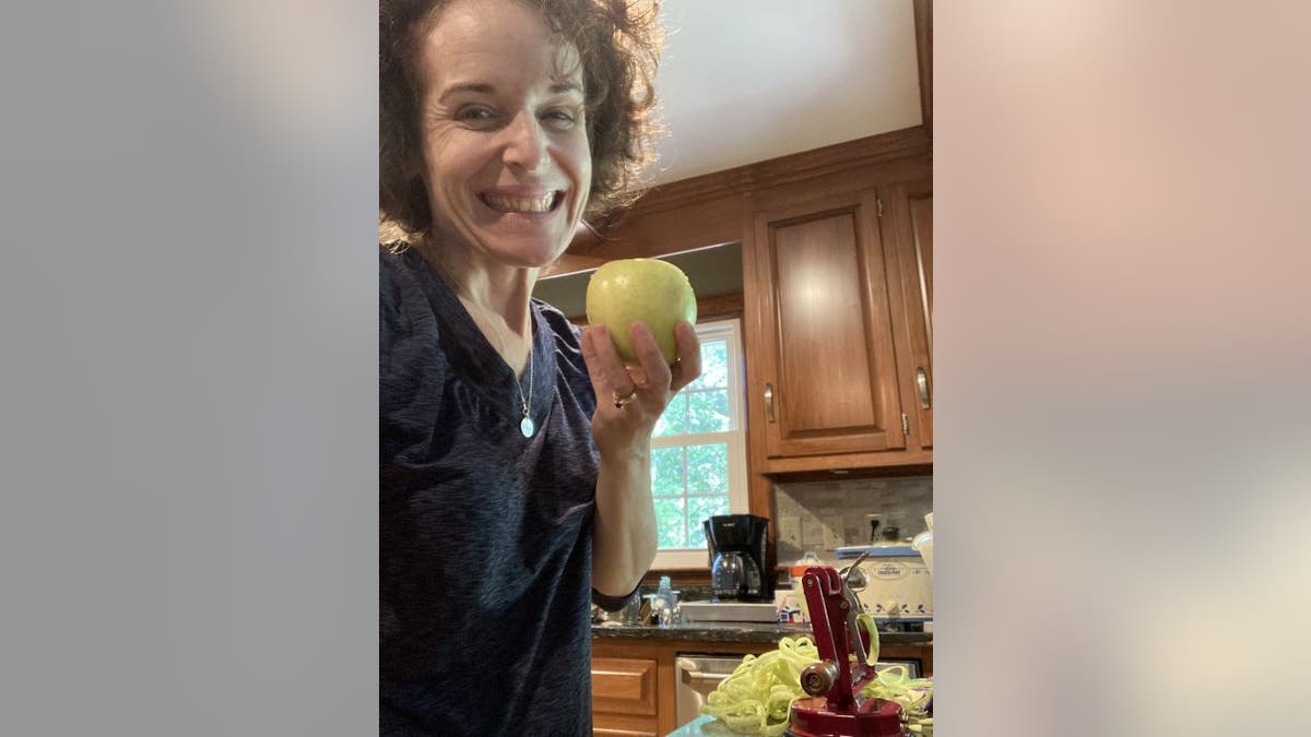 Wendy Schofer holds apple in her kitchen