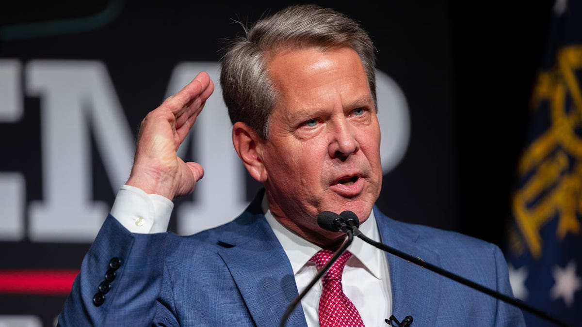 Republican Georgia Gov. Brian Kemp gestures in a blue suit at a campaign event