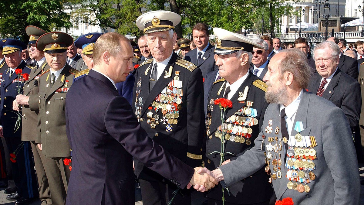 Russian President Vladimir Putin (C) shakes hands with WWII veterans after a wreath laying ceremony at the Unknown Soldier Tomb in Moscow, May 8, 2002. Russia will celebrate the Victory Day on May 9.