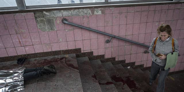AVERTISSEMENT : IMAGE GRAPHIQUE : Une femme marche à côté du corps d'un homme tué lors d'un bombardement à Kharkiv, dans l'est de l'Ukraine, le jeudi 26 mai.