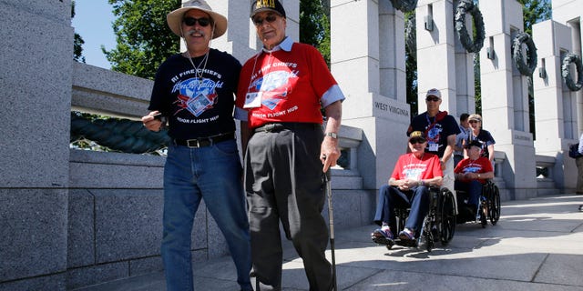 World War II veterans are escorted to a ceremony at the National World War II Memorial marking the 70th anniversary of the D-Day invasion of Europe on June 6, 1944, in Washington, June 6, 2014.