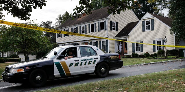 In this Sept. 29, 2014, file photo, a Montgomery Township Police officer sits in front of the partially burned home of John and Joyce Sheridan in Montgomery Township, N.J. 