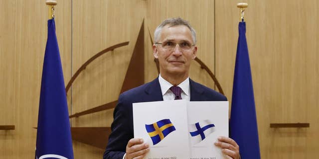 Le secrétaire général de l'OTAN, Jens Stoltenberg, affiche des documents alors que la Suède et la Finlande ont demandé leur adhésion à Bruxelles, Belgique, le 18 mai.
