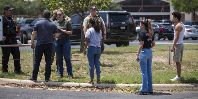 A law enforcement officer speaks with people outside Uvalde High School after shooting was reported earlier on Tuesday, May 24, 2022, at Robb Elementary School in Uvalde, Texas. 