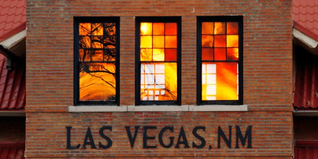 Reddened by wildfire smoke, the sun is seen reflected off glass at the train station in Las Vegas, N.M., on Saturday, May 7, 2022. Area residents have been on and off of evacuation orders of the past month as fires grow and move with intense and unpredictable winds.