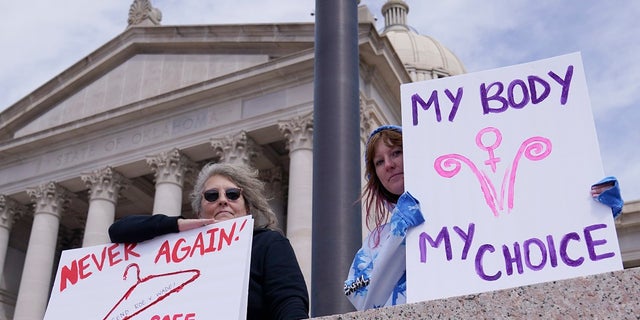 Dani Thayer, a la izquierda, y Marina Lanae, a la derecha, ambas de Tulsa, Oklahoma, sostienen carteles a favor del aborto en el Capitolio estatal, el 13 de abril en la ciudad de Oklahoma.  La Legislatura estatal de Oklahoma, liderada por los republicanos, aprobó varias restricciones contra el aborto en las últimas semanas, como parte de un movimiento en los estados conservadores para restringir los derechos reproductivos de las mujeres. 