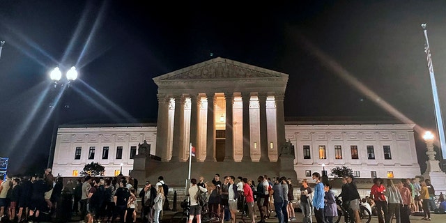 A crowd of people gather outside the Supreme Court, Monday night, May 2, 2022 in Washington.