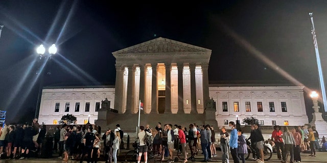 A crowd of people gather outside the Supreme Court, Monday night, May 2, 2022 in Washington. A draft opinion circulated among Supreme Court justices suggests that earlier this year a majority of them had thrown support behind overturning the 1973 case Roe v. Wade that legalized abortion nationwide, according to a report published Monday night in Politico. It’s unclear if the draft represents the court’s final word on the matter.  The Associated Press could not immediately confirm the authenticity of the draft Politico posted, which if verified marks a shocking revelation of the high court’s secretive deliberation process, particularly before a case is formally decided. (AP Photo/Anna Johnson)