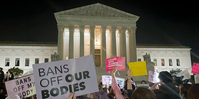 A crowd of people gather outside the Supreme Court, Monday night, May 2, 2022 in Washington following reports of a leaked draft opinion by the court overturning Roe v. Wade. (AP Photo/Anna Johnson)