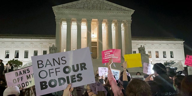 A crowd of people gather outside the Supreme Court, Monday night, May 2, 2022, in Washington.