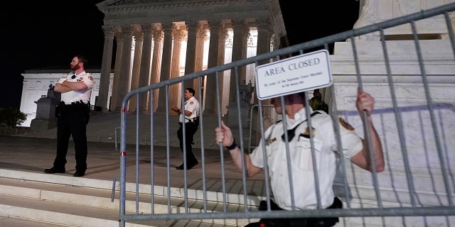 Police move barricades in place as a crowd of people gather outside the Supreme Court, Monday night, May 2, 2022, in Washington.