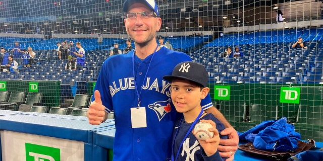 Nine-year-old Derek Rodriguez poses for a photo Wednesday, 可能 4, 2022, in Toronto with Mike Lanzillotta, the Toronto Blue Jays fan who caught the ball on a home run by New York Yankees' Aaron Judge on Tuesday and handed it to Derek. 在星期三, Judge signed the ball and met Derek before the game.