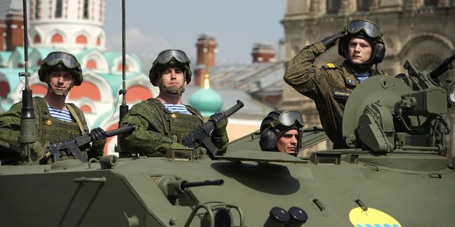 Krievijas armijas karavīri stāv militārajā transportlīdzeklī, kas ripo Uzvaras dienas militārās parādes mēģinājuma laikā Maskavā, Krievijā, sestdien, 2022. gada 7. maijā. Parāde notiks Sarkanajā laukumā Maskavā 9. maijā, lai atzīmētu 77 gadus. uzvaras.  2. pasaules karā. 