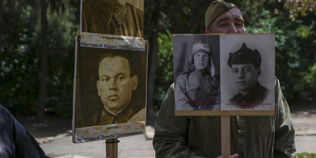 Israeli-Russian relatives of World War II veterans hold their photos during a ceremony marking the 77th anniversary of the end of World War II at a memorial site for Jewish fighters, in Haifa, Israel, Monday, May 9, 2022.