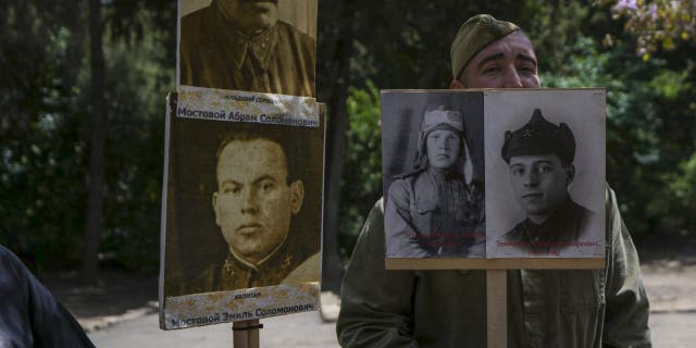 Israeli-Russian relatives of World War II veterans hold their photos during a ceremony marking the 77th anniversary of the end of World War II at a memorial site for Jewish fighters, in Haifa, Israel, Monday, May 9, 2022.