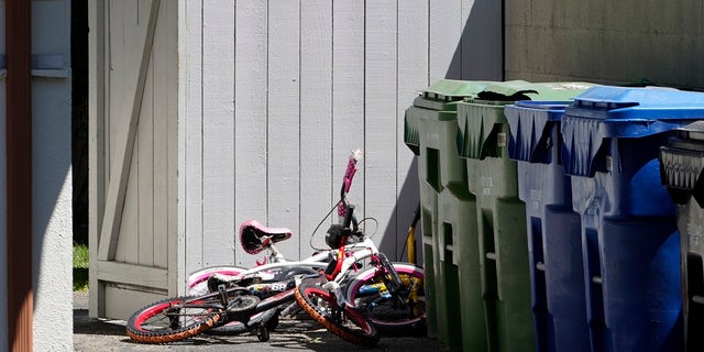 Childrens' bycicles are left near trash cans at the scene where three children were found dead inside a Los Angeles home. 