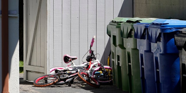 Childrens' bycicles are left near trash cans at the scene where three children were found dead inside a Los Angeles home. 