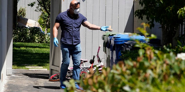 An unidentified man puts a wooden bath brush in the trash can at a ranch-style house in the West Hills neighborhood of the San Fernando Valley in Los Angeles, Monday, May 9, 2022.