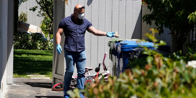 An unidentified man puts a wooden bath brush in the trash can at a ranch-style house in the West Hills neighborhood of the San Fernando Valley in Los Angeles, Monday, May 9, 2022.