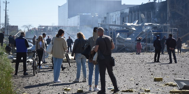 People stand near a destroyed building on the outskirts of Odesa, 우크라이나, 화요일, 할 수있다 10, 2022. The Ukrainian military said Russian forces fired seven missiles a day earlier from the air at the crucial Black Sea port of Odesa, hitting a shopping center and a warehouse. 