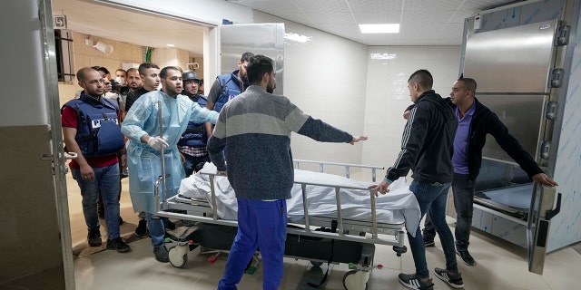 Journalists and medics wheel the body of Shireen Abu Akleh, a journalist for Al Jazeera network, into the morgue inside the Hospital in the West Bank town of Jenin, Wednesday, May 11, 2022.