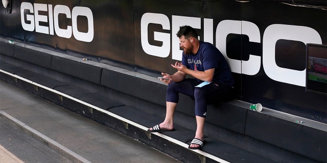 Cleveland Guardians' Bryan Shaw talks on the phone in the dugout after the game between the Chicago White Sox and the Guardians was postponed due to multiple positive COVID-19 tests within the Guardians organization, Wednesday, May 11, 2022, in Chicago.