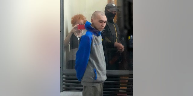 Russian army Sergeant Vadim Shishimarin, 21, is seen behind a glass during a court hearing in Kyiv, Ukraine, Friday, May 13, 2022. The trial of a Russian soldier accused of killing a Ukrainian civilian opened Friday, the first war crimes trial since Moscow's invasion of its neighbor. (AP Photo/Efrem Lukatsky)