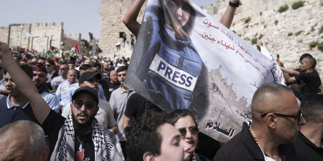 Mourners hold a banner depicting slain Al Jazeera veteran journalist Shireen Abu Akleh as they walk from the Old City of Jerusalem to her burial site May 13, 2022.