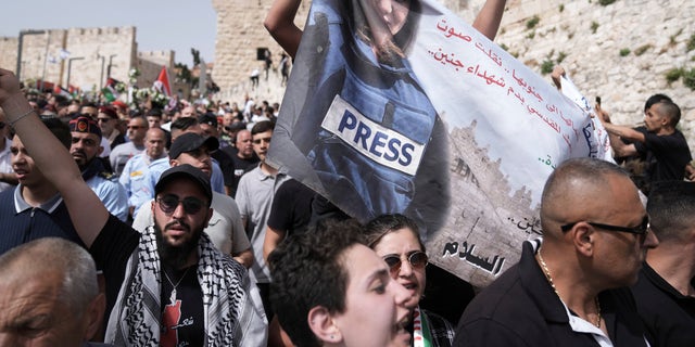 Mourners hold a banner depicting slain Al Jazeera veteran journalist Shireen Abu Akleh as they walk from the Old City of Jerusalem to her burial site, Friday, May 13, 2022. Abu Akleh, a Palestinian-American reporter who covered the Mideast conflict for more than 25 years, was shot dead Wednesday during an Israeli military raid in the West Bank town of Jenin.