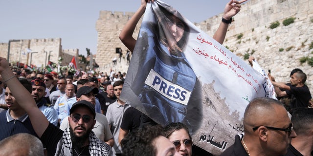 Mourners hold a banner depicting slain Al Jazeera veteran journalist Shireen Abu Akleh as they walk from the Old City of Jerusalem to her burial site, Friday, May 13, 2022. Abu Akleh, a Palestinian-American reporter who covered the Mideast conflict for more than 25 years, was shot dead Wednesday during an Israeli military raid in the West Bank town of Jenin.