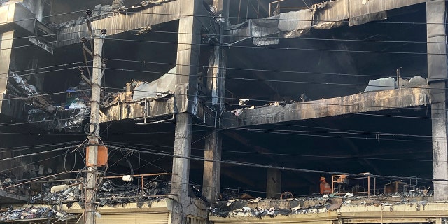 People examine the site of a fire in New Delhi, India, Saturday, May 14, 2022. A massive fire erupted Friday evening in a four-story commercial building in the Indian capital, killing more than two dozen people and leaving several others injured, the fire control room said. (G3 Box News Photo/Shonal Ganguly)