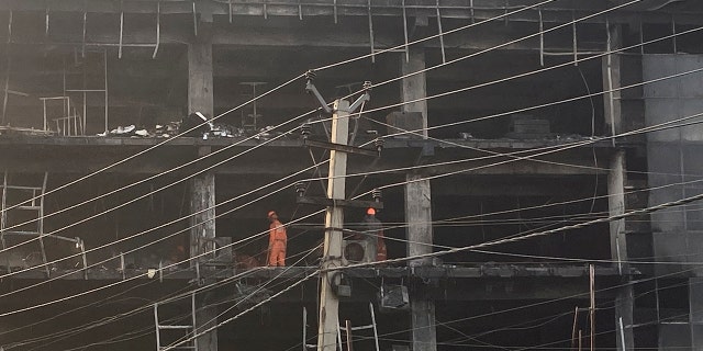 Rescuers work at the site of a fire in New Delhi, India, Saturday, May 14, 2022. A massive fire erupted Friday evening in a four-story commercial building in the Indian capital, killing more than two dozen people and leaving several others injured, the fire control room said. (AP Photo/Shonal Ganguly)