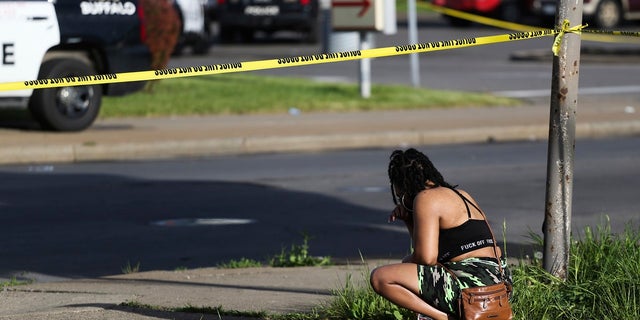 A passerby watches as police investigate after a supermarket shooting on Saturday, May 14, 2022 in Buffalo, New York 