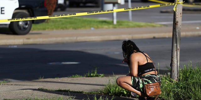 A passerby watches as police investigate after a supermarket shooting on Saturday, May 14, 2022 in Buffalo, New York