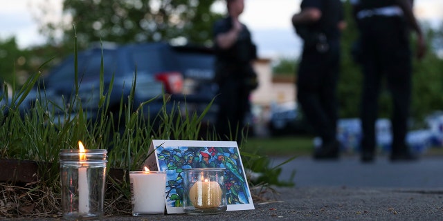 Police walk by a small memorial as they investigate after a shooting at a supermarket on Saturday, May 14, 2022, in Buffalo, N.Y.