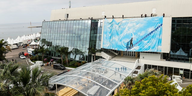 Festival workers pull the official poster into place at the Grand Theatre Lumiere during preparations for the 75th international film festival, Cannes, southern France, Domenica, Maggio 15, 2022. The Cannes film festival runs from May 17th until May 28th 2022. (AP Photo/Dejan Jankovic)
