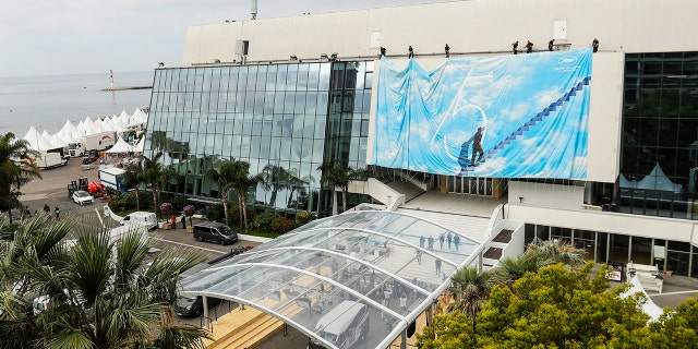 Festival staff are putting up an official billboard at the Lumiere Theater in preparation for the 75th International Film Festival in Cannes, southern France, on Sunday, May 15, 2022. The Cannes Film Festival takes place from 17 to 28 May 2022. (AP Photo / Dejan Jankovic)