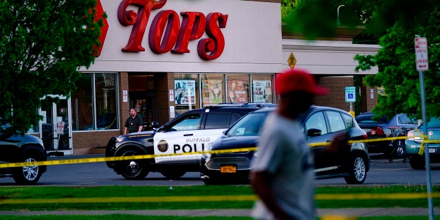 A person walks past the scene of a shooting at a supermarket, in Buffalo, N.Y., Sunday, May 15, 2022. 