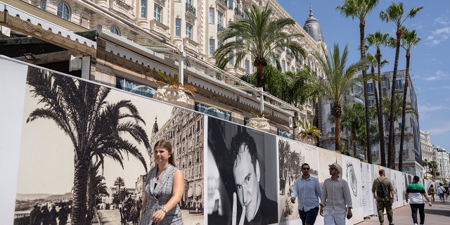 People walk along the Croisette in front of the 75th Cannes International Film Festival, Southern France, Monday, May 16, 2022. The Cannes Film Festival runs from 17 to 28 May 2022 (AP Photo / Petros Giannakouris)