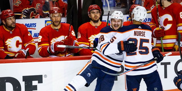 Edmonton Oilers winger Zach Hyman, sinistra, celebrates his goal against the Calgary Flames with Darnell Nurse as Flames on the bench watch during the third period of Game 2 of an NHL hockey Stanley Cup playoffs second-round series Friday, Maggio 20, 2022, in Calgary, Alberta. 