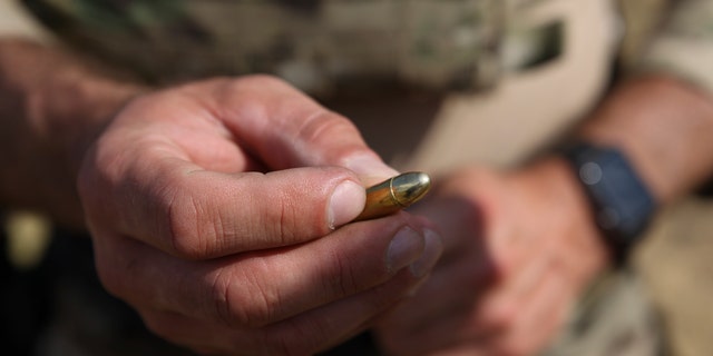 Polish instructor, Dariusz Tomysek, shows a pistol bullet during a practice for Belarusian volunteers at a shooting range near Warsaw, 波兰, 在周五, 可能 20, 2022. 