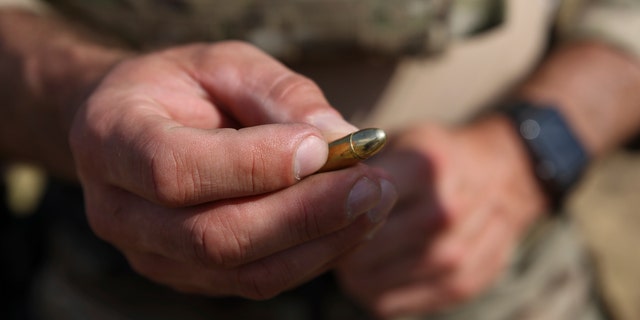 Polish instructor, Dariusz Tomysek, shows a pistol bullet during a practice for Belarusian volunteers at a shooting range near Warsaw, Poland, on Friday, May 20, 2022. 