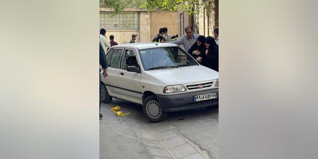 In this photo provided by Islamic Republic News Agency, IRNA, family members of Col. Hassan Sayyad Khodaei weep over his body at his car after being shot by two assailants in Tehran, Iran, Sunday, May 22, 2022. Hassan Sayyad Khodaei, a senior member of Iran's powerful Revolutionary Guard, was killed outside his home in Tehran on Sunday by unidentified gunmen on a motorbike, state TV reported.