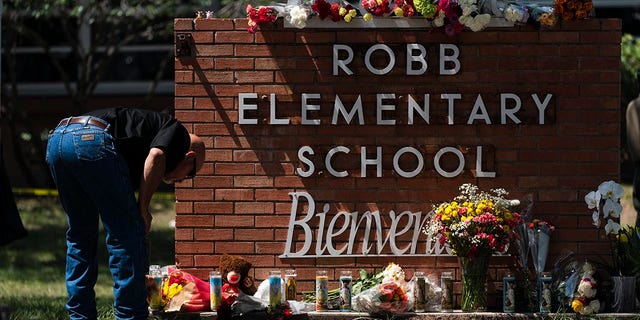 A law enforcement personnel lights a candle outside Robb Elementary School in Uvalde, Texas, Wednesday, May 25, 2022. (AP Photo/Jae C. Hong)