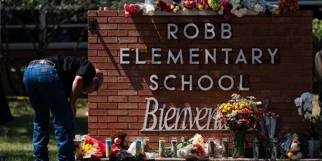 Un miembro de la policía enciende una vela afuera de la Escuela Primaria Robb en Uvalde, Texas, el miércoles 25 de mayo de 2022.