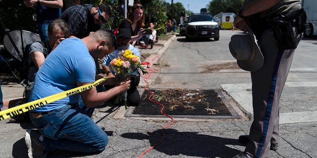 Joseph Avila, left, prays while holding flowers honoring the victims killed in Tuesday's shooting at Robb Elementary School in Uvalde, Texas, Wednesday, May 25, 2022. Desperation turned to heart-wrenching sorrow for families of grade schoolers killed after an 18-year-old gunman barricaded himself in their Texas classroom and began shooting, killing at least 19 fourth-graders and their two teachers. 