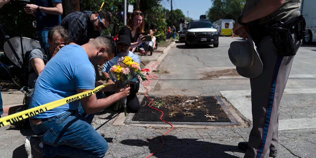 Joseph Avila, left, prays while holding flowers honoring the victims killed in Tuesday's shooting at Robb Elementary School in Uvalde, Texas, Wednesday, May 25, 2022. Desperation turned to heart-wrenching sorrow for families of grade schoolers killed after an 18-year-old gunman barricaded himself in their Texas classroom and began shooting, killing at least 19 fourth-graders and their two teachers.