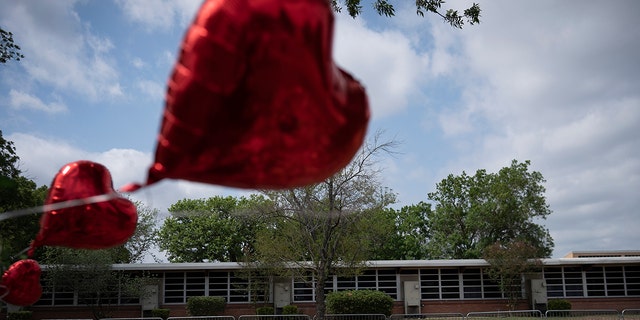 A heart-shaped balloon flies decorating a memorial site outside Robb Elementary School in Uvalde, Texas, Monday, May 30, 2022.
